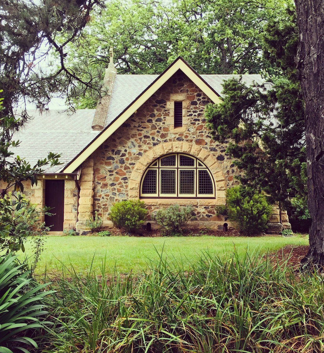 A stone cottage surrounded by lush garden greenery