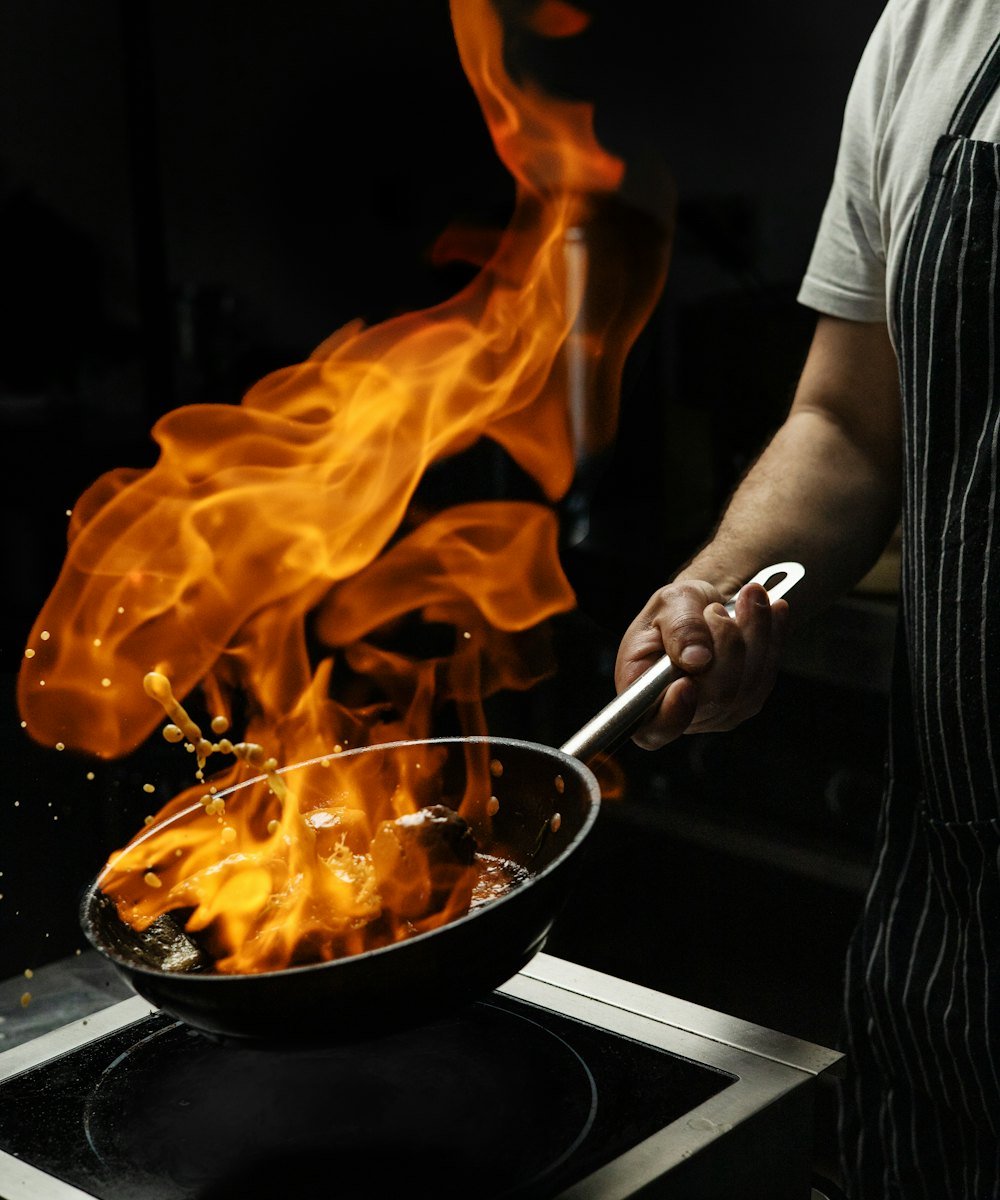 Chef tossing a flaming pan over a stove