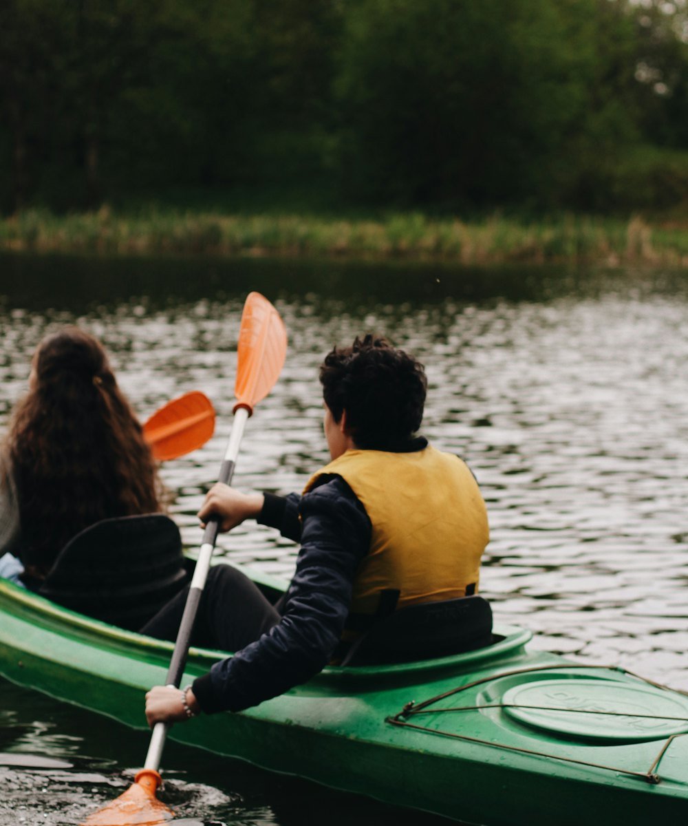 Two people paddling a kayak on a forest-lined lake