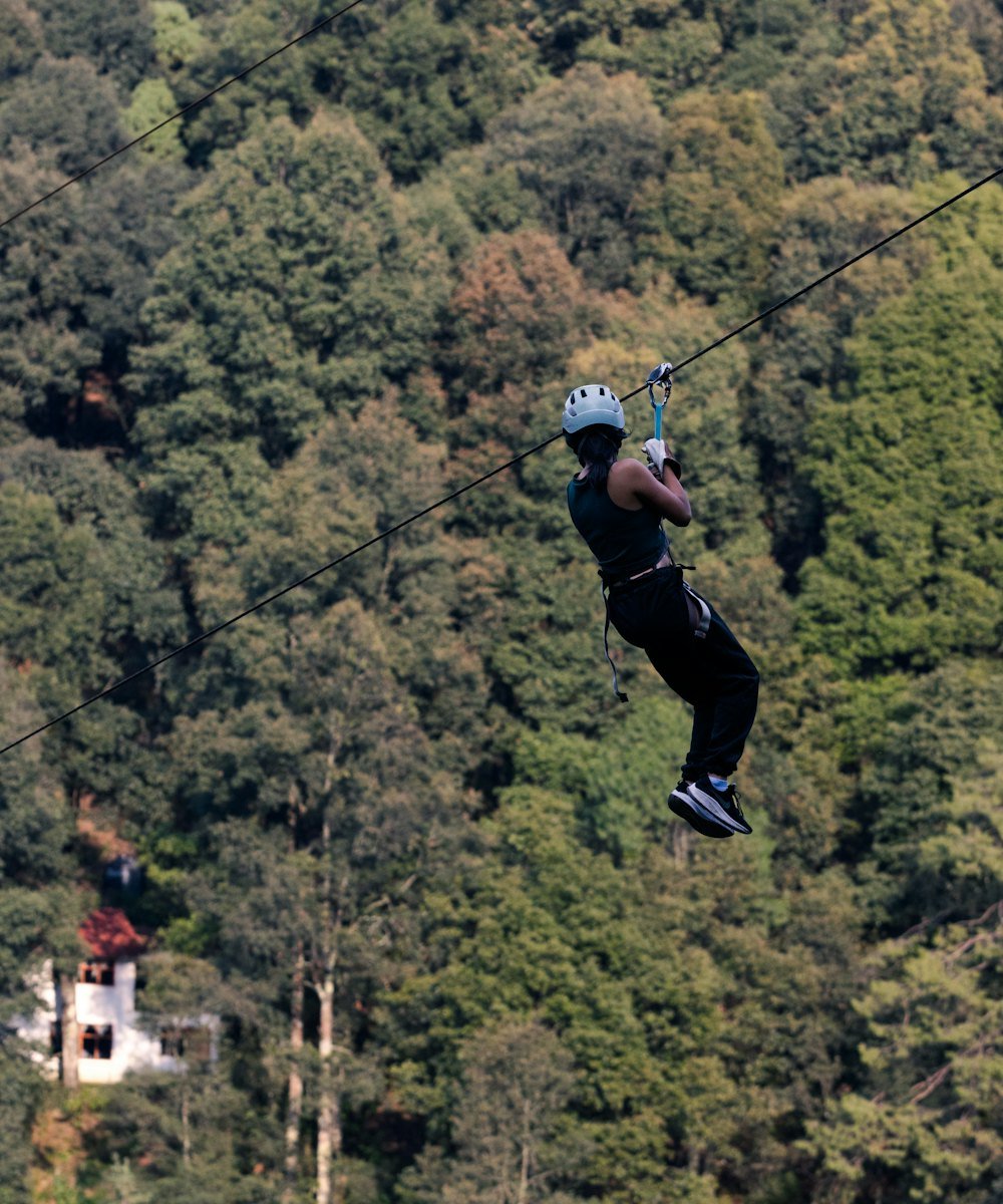 Rider on a zip line above a dense green forest
