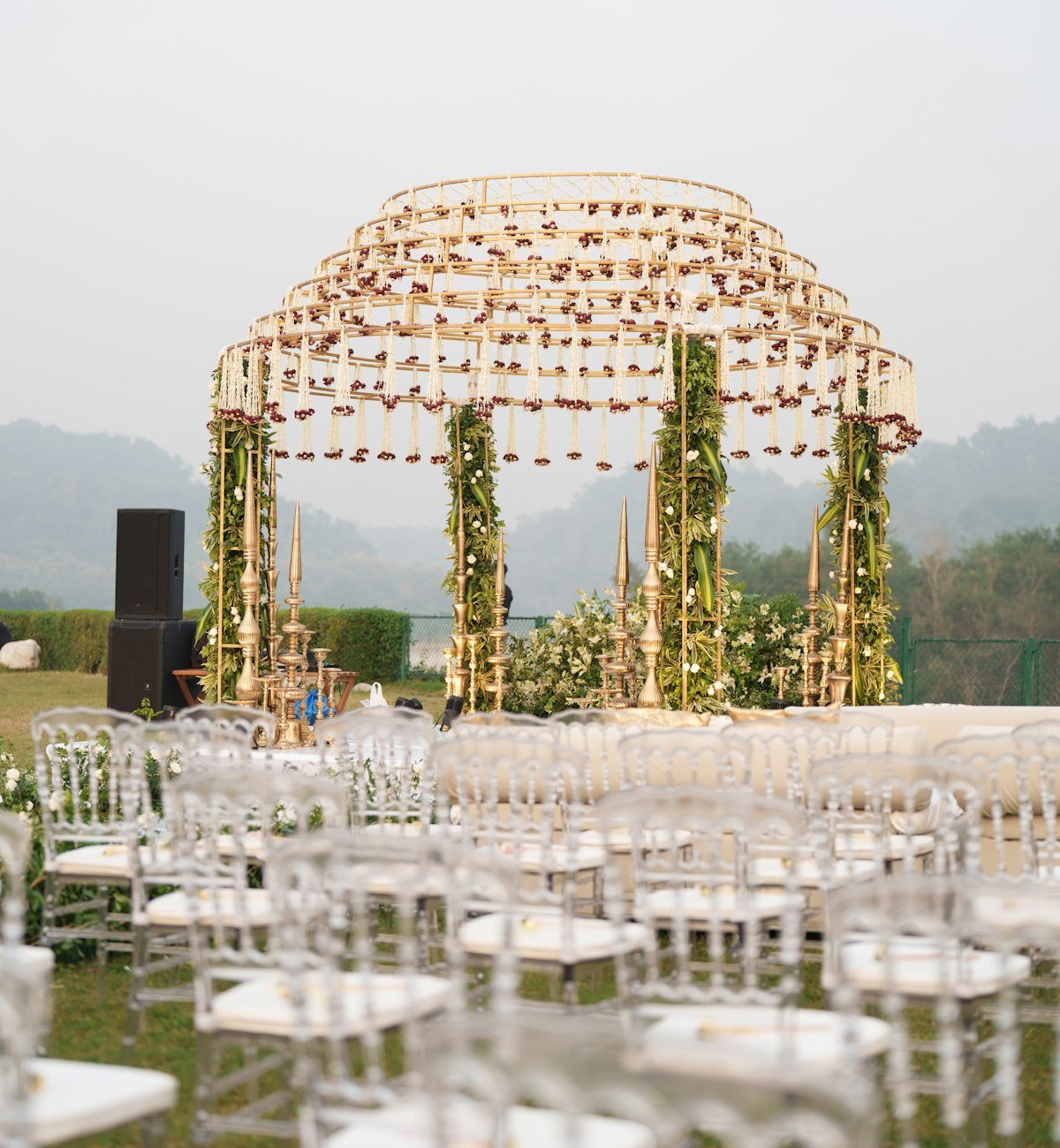 Floral wedding mandap set up outdoors with misty hills behind