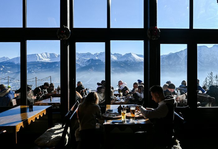 Diners at tables beside large windows with mountain views
