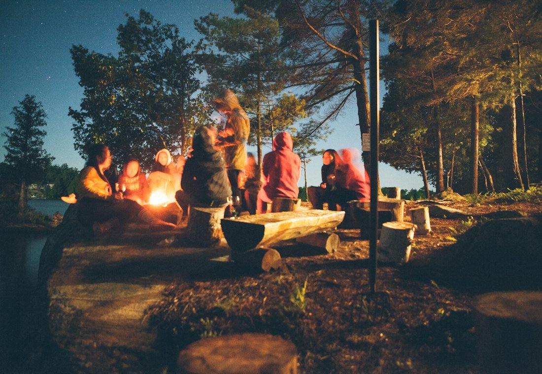 Friends gathered around a bonfire under the trees