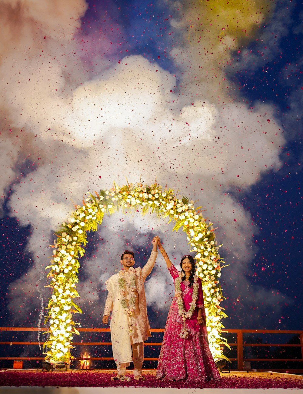 Couple under a lit floral arch