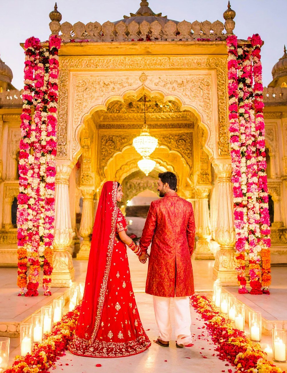 Bride and groom in traditional attire at a floral entrance